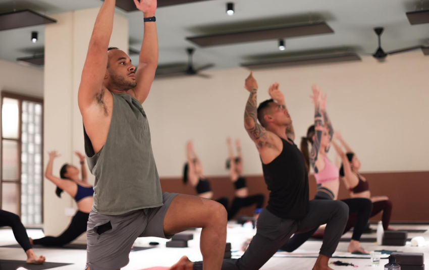 Male and female practitioners holding a yoga pose during a class