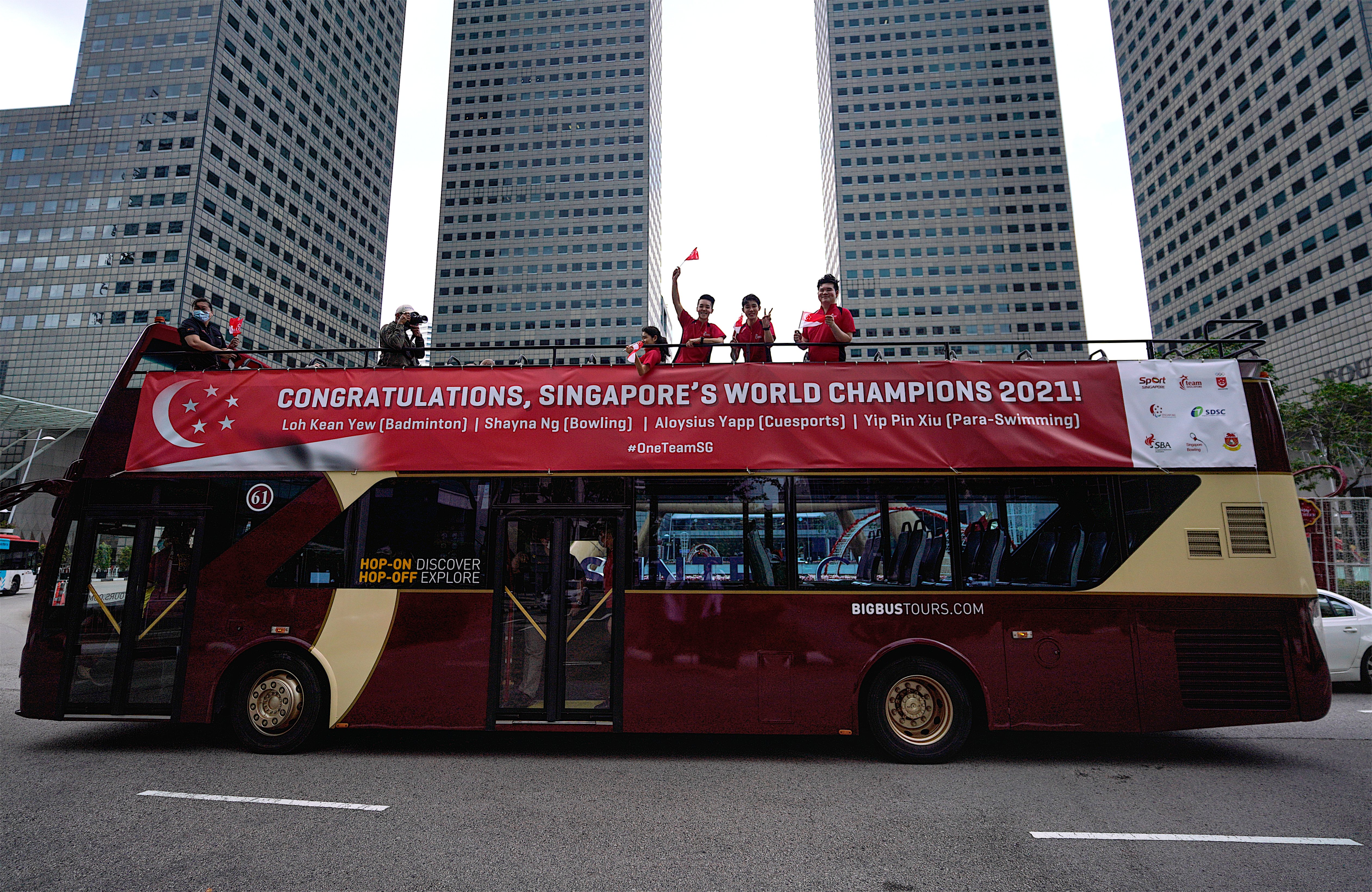 Athletes greeting crowd from open-top bus