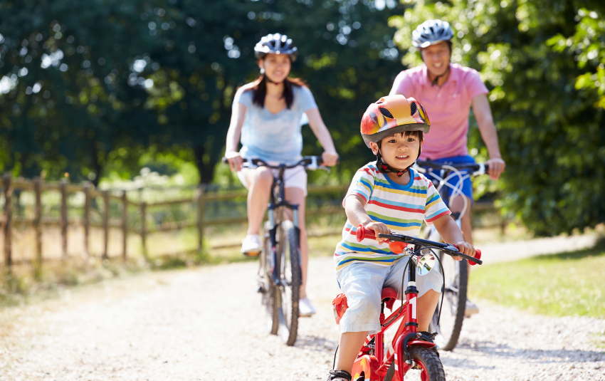 Young boy cycling at the park with his parents
