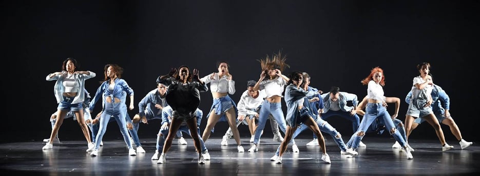Hip hop dancers in white and denim outfits performing on stage