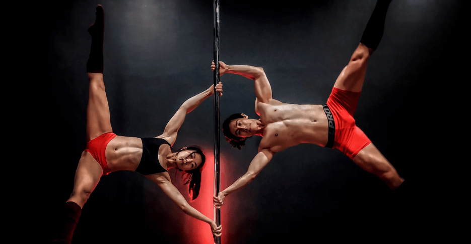 Man and woman hanging sideways on dancing pole