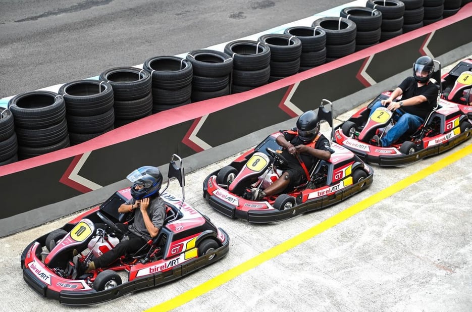 Three men riding on the red go-karts getting ready to race