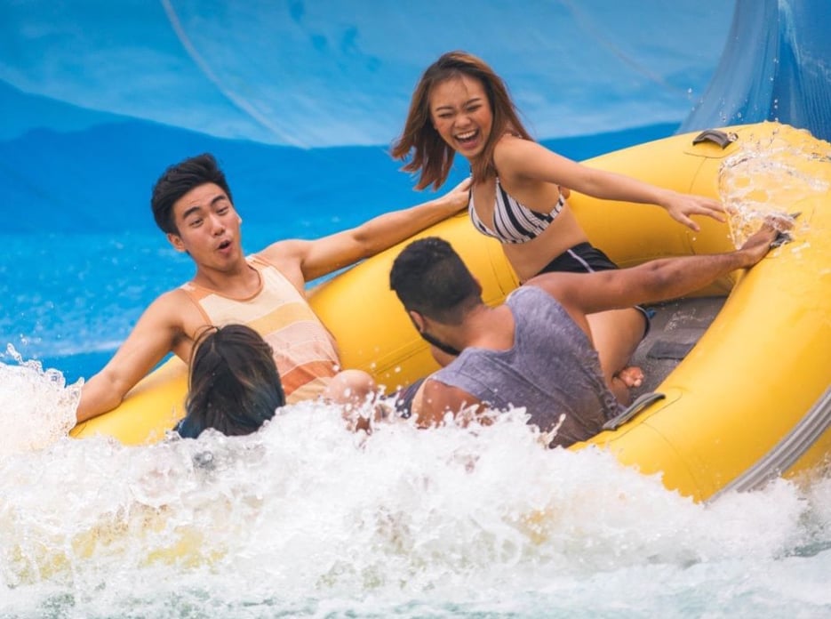 Woman laughing while riding a yellow inflatable boat with her friends